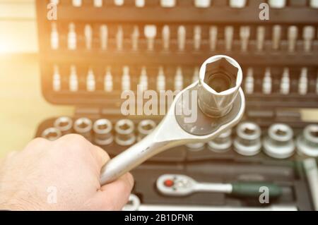 car repair. hand with a wrench on the background of a toolbox. Bits, screwdrivers, wrenches of different sizes Stock Photo