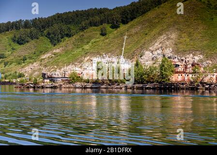 Clear lake Baikal water with green forest on the hills and old rusty ship in summer Stock Photo