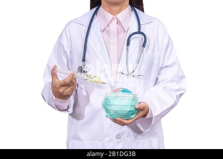 doctor in medical gown using an vaccine syringe on the globe with hygiene mask in hand. the outbreak situation of Coronavirus 2019 infection or Covid- Stock Photo