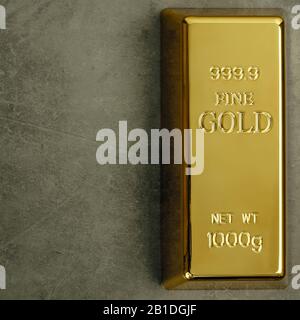 Ingot of pure gold metal bullion on a gray textured background Stock Photo