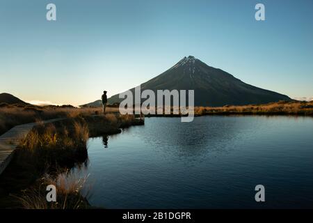 Admiring Mt Taranaki at sunrise from Pouakai tarn Stock Photo