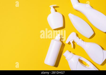 Detergent bottles and chemical cleaning supplies on yellow background. Top view. Copy space. Flat lay Stock Photo