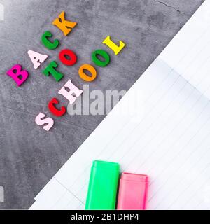 The layout of school supplies on a dark gray background. Top view, the sun's rays from the side. Back to school. Flat lay Stock Photo