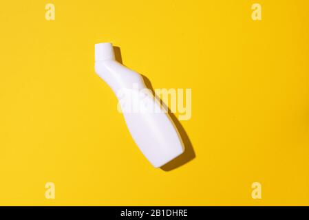 White plastic bottle of cleaning product, household chemicals or liquid laundry detergent on yellow background. Top view. Flat lay. Copy space. Detergent bottle. Stock Photo