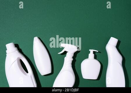 Composition with plastic bottles of cleaning products over green background. Top view. Flat lay. Copy space. Plastic waste. Detergent bottle pattern. Stock Photo