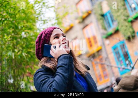 Neals´Yard street, London. A girl with a wool hat takes a picture with the mobile phone in the street of a picturesque town Stock Photo