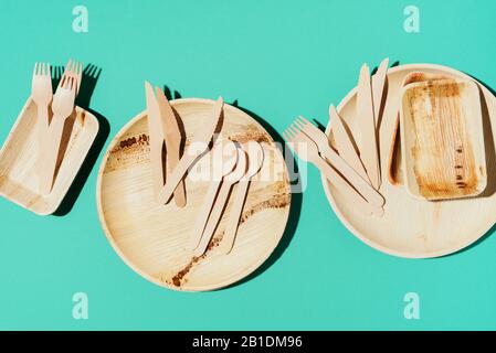 Eco craft paper tableware. Paper cups, bamboo wood dishes and wooden cutlery on blue background. Recycling or zero waste concept. Top view. Copy space. Stock Photo