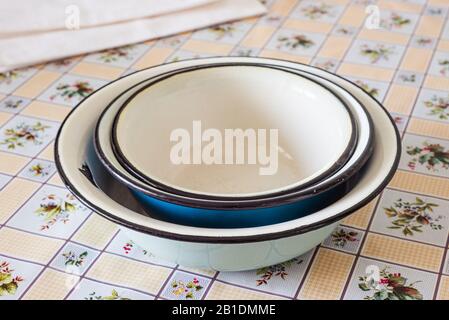 Pile of old enamel dishes, or bowls, on a kitchen table Stock Photo