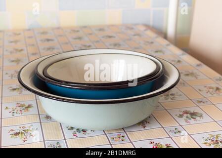Pile of old enamel dishes, or bowls, on a kitchen table Stock Photo