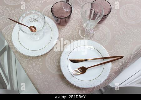 white plates on a served table with cutlery and flowers, top view, Stock Photo