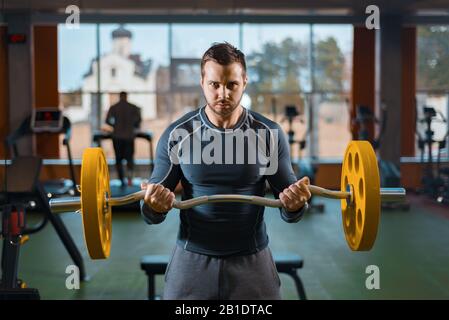 sports guy is training with a barbell. athletic man doing weight in the gym Stock Photo