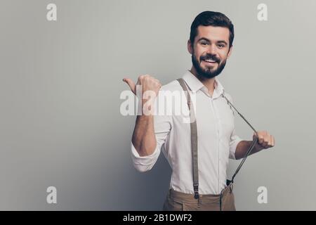 Positive confident cool man real estate agent point forefinger copyspace indicate ads promo recommend suggest select pull suspenders wear white pants Stock Photo