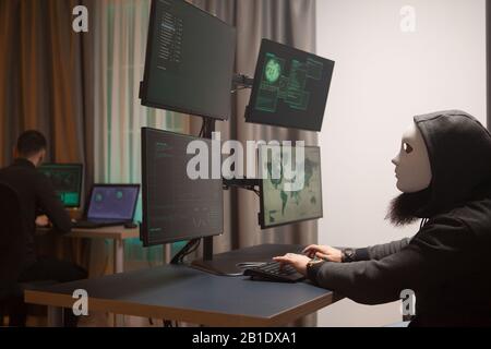 Cyber criminal wearing a white mask while testing government system. Cyber hacker. Stock Photo