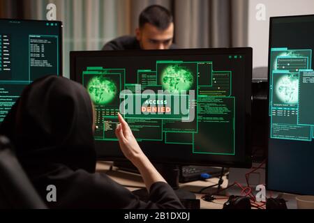 Back view of angry female hacker after access denied showing on computer desktop. Stock Photo