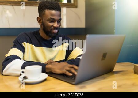 Serious african-american man using laptop studying on computer in public place Stock Photo