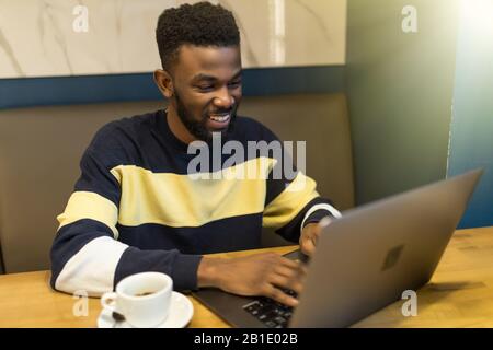 Serious african-american man using laptop studying on computer in public place Stock Photo
