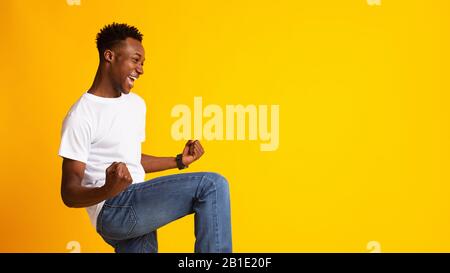 Excited young african man expressing success on yellow Stock Photo
