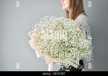 White gypsophila. Beautiful bouquet of mixed flowers in womans hands. the work of the florist at a flower shop. Fresh cut flower. Stock Photo