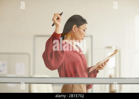 Waist up portrait of elegant Asian businesswoman writing on glass wall while planning project in modern office, copy space Stock Photo