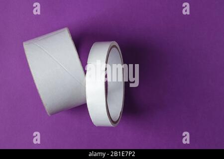 Two rolls of sticky adhesive scotch tape on purple background Stock Photo
