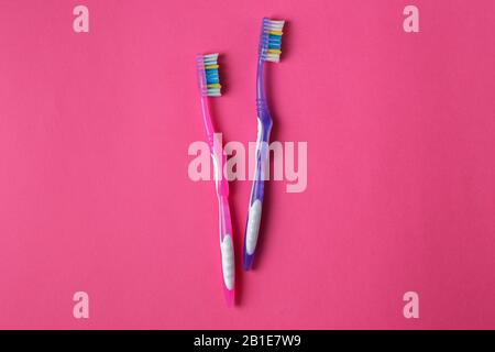 The old pink and purple toothbrushes used expired (damaged) on the pink background. Plastic pollution concept Stock Photo
