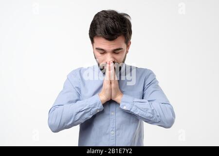 Religious expressive hispanic man praying in studio on white isolated background Stock Photo