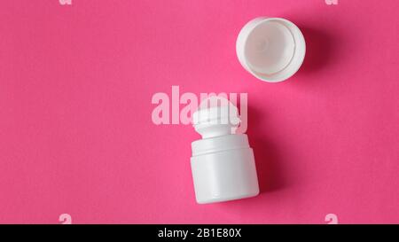 White roll on deodorant with cap on pink background with copy space Stock Photo