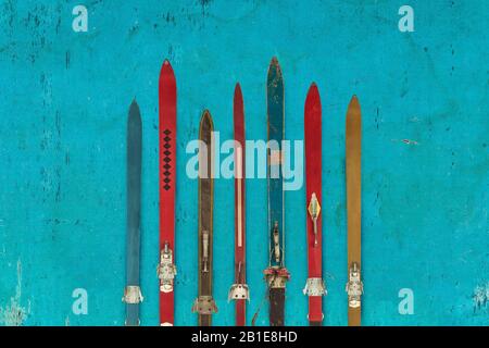 Collection of vintage wooden weathered ski's in front of a blue eroded background Stock Photo