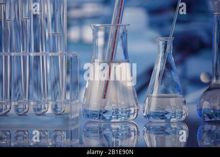 Science laboratory. Beakers, test-tubes and microscope on glass table in the laboratory. Stock Photo