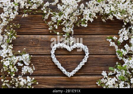 Close-up photo of Beautiful white Flowering Cherry Tree branches with white heart shape. Wedding, engagement or betrothal concept on vintage wooden ba Stock Photo