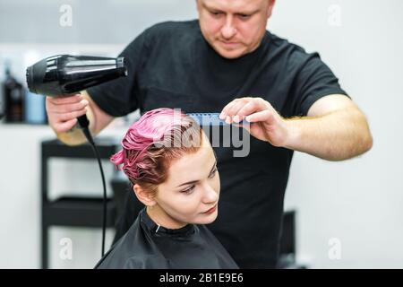 Close up of professional hairdresser is drying female hair, back view. Stock Photo