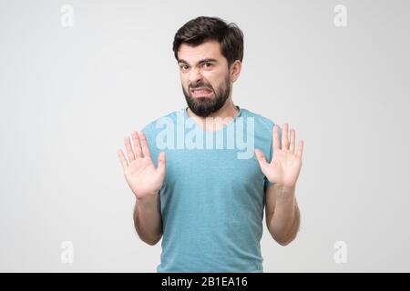 Handsome hispanic man making stop sign refusing to take the award. Studio shot Stock Photo