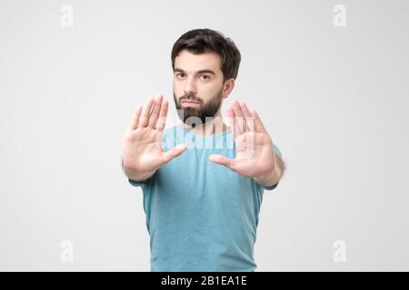 Handsome hispanic man making stop sign refusing to take the award. Studio shot Stock Photo