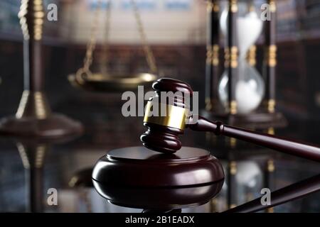 Law and justice concept. Judge’s gavel, hourglass and scale on the shining wooden brown table. Stock Photo