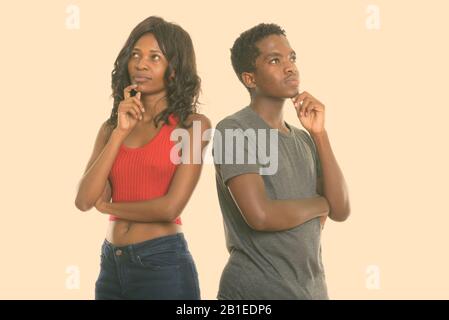 Studio shot of black African sister and brother thinking together Stock Photo