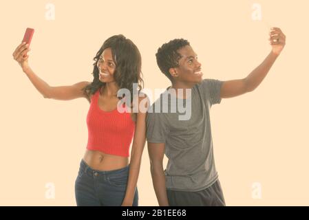 Happy young African sister and brother while taking selfie picture with mobile phone together Stock Photo