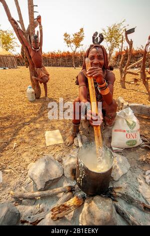 Himba woman cooking their staples food made with corn meal at his village near Epupa Falls, Namibia Stock Photo