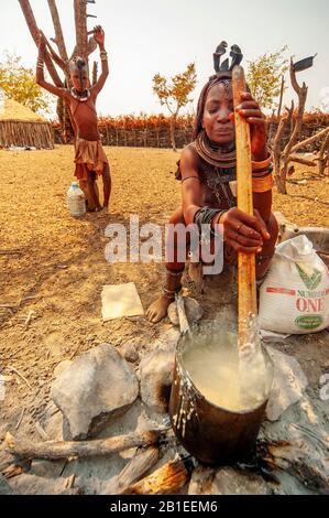 Himba woman cooking their staples food made with corn meal at his village near Epupa Falls, Namibia Stock Photo