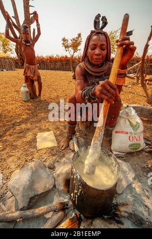 Himba woman cooking their staples food made with corn meal at his village near Epupa Falls, Namibia Stock Photo