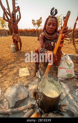 Himba woman cooking their staples food made with corn meal at his village near Epupa Falls, Namibia Stock Photo