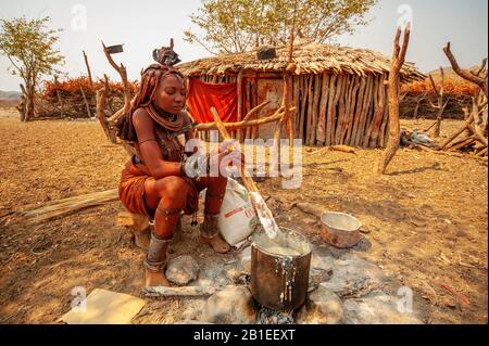 Himba woman cooking their staples food made with corn meal at his village near Epupa Falls, Namibia Stock Photo