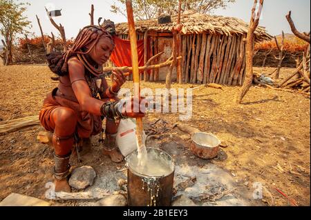 Himba woman cooking their staples food made with corn meal at his village near Epupa Falls, Namibia Stock Photo