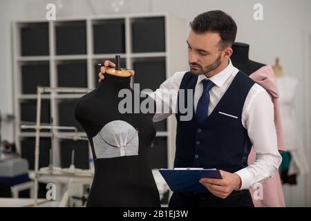 Male tailor touching dummy, creating new model Stock Photo