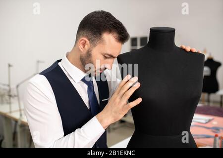 Male fashion designer bending head down on dummy Stock Photo