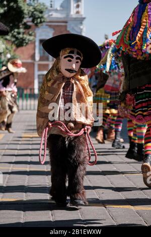 A young boy in cowboy outfit, part of a Litter of Chivarrudos,type of Huehues in traditional Mexican costumes at Carnival, walking by others Stock Photo