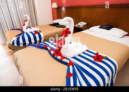 Towel sculptures decorated with hibiscus flowers, made by room service personnel, stand on beds in a hotel in Jordan. Stock Photo