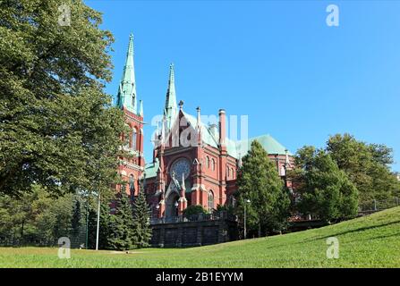 Famous gothic red church historic architecture landmark in Helsinki, Finland with blue sky and vivid green grass. City Europe travel photography Stock Photo