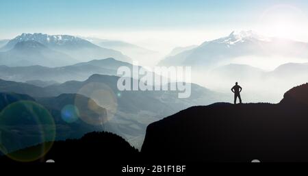 Spectacular mountain ranges silhouettes. Man reaching summit enjoying freedom. Stock Photo
