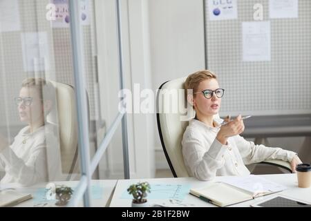 High angle view at modern short haired woman wearing glasses sitting in big office chair at work, female boss concept, copy space Stock Photo