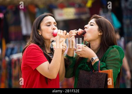 Two women eating flavored ice gola dipped in syrup Stock Photo